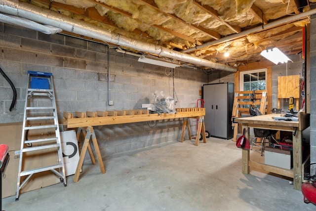 unfinished basement featuring concrete block wall and a workshop area