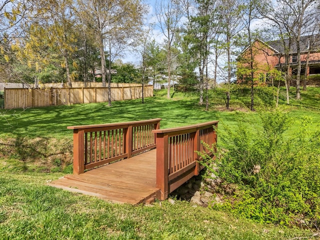 wooden terrace featuring a yard and fence