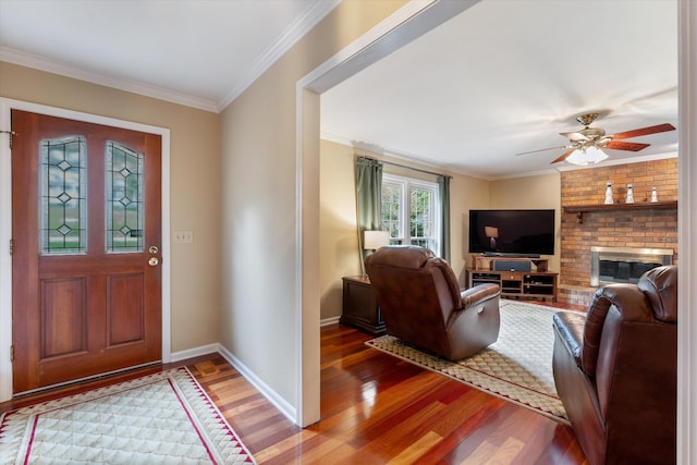 foyer entrance with light wood-type flooring, a brick fireplace, crown molding, and baseboards