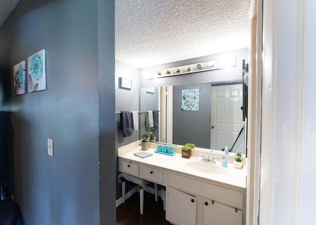 bathroom featuring vanity, a textured ceiling, baseboards, and wood finished floors