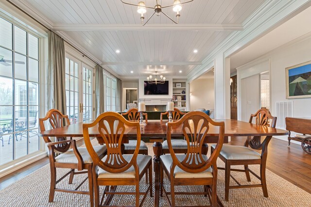 4535 Peytonsville Rd, Franklin, TN 37064 - dining area featuring a notable chandelier, a warm lit fireplace, visible vents, beam ceiling, and wood finished floors