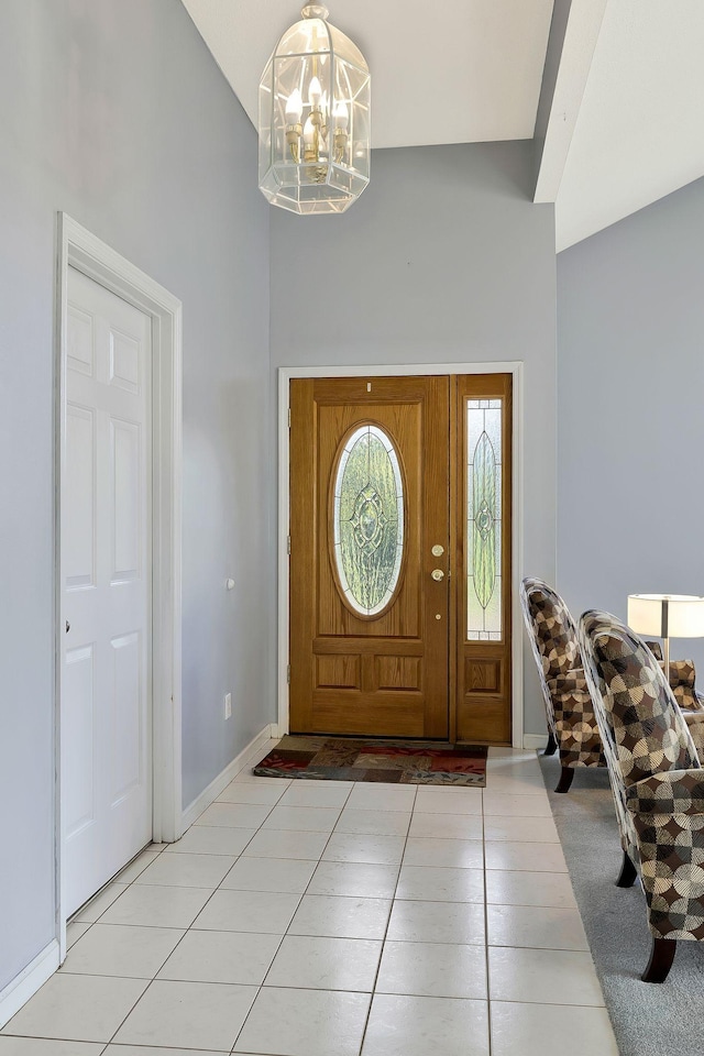 foyer with light tile patterned floors, baseboards, a notable chandelier, and a towering ceiling