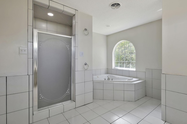 bathroom with tile patterned floors, visible vents, a bath, and a stall shower