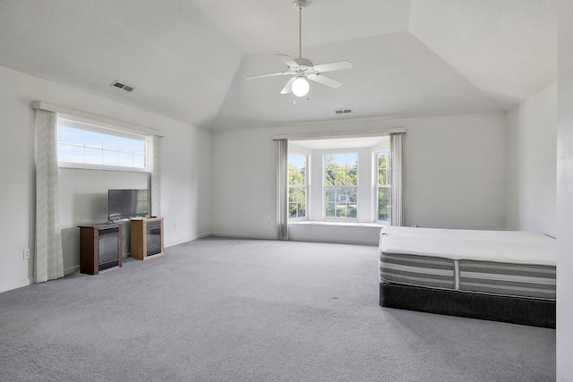 unfurnished bedroom featuring carpet, multiple windows, vaulted ceiling, and visible vents