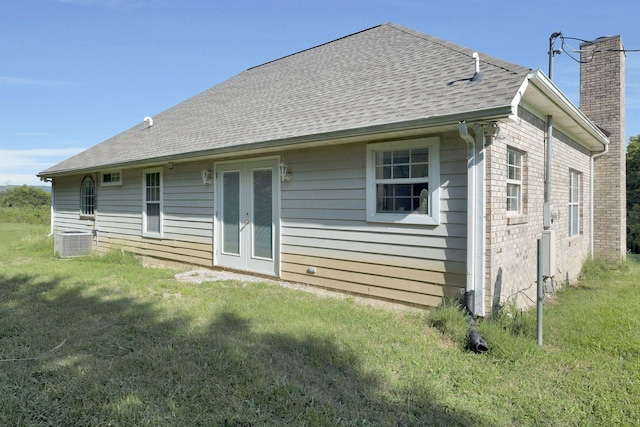 back of house with french doors, a chimney, central air condition unit, and a lawn