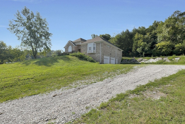exterior space featuring a lawn, brick siding, driveway, and an attached garage