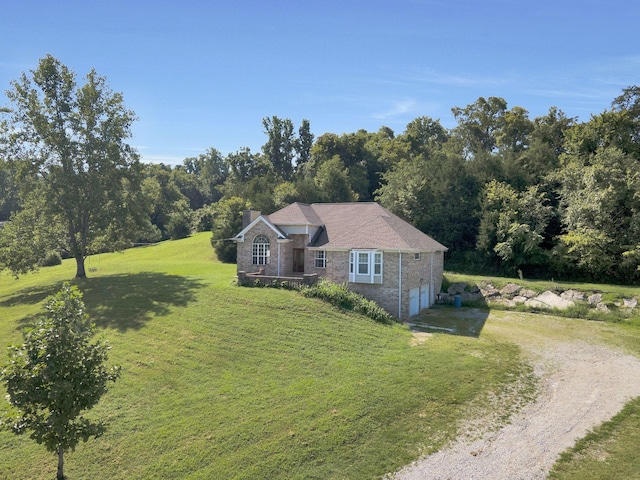 view of front of property featuring a front yard, an attached garage, a chimney, brick siding, and driveway