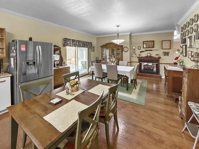 dining room with crown molding, light wood finished floors, and a multi sided fireplace