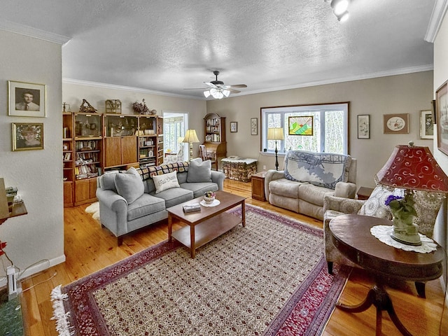 living area featuring crown molding, wood finished floors, baseboards, and a ceiling fan