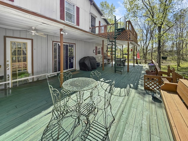 wooden deck with grilling area, outdoor dining space, ceiling fan, and stairway