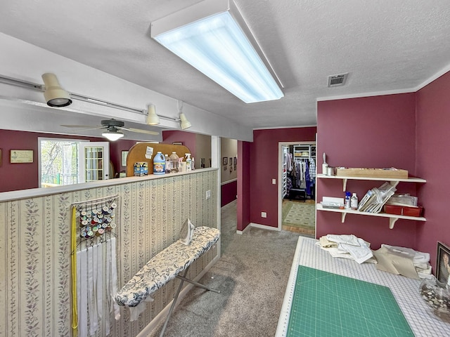 interior space with carpet flooring, visible vents, a textured ceiling, and ceiling fan