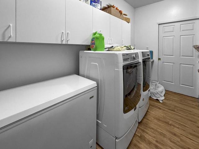 laundry room with cabinet space, washing machine and clothes dryer, and wood finished floors