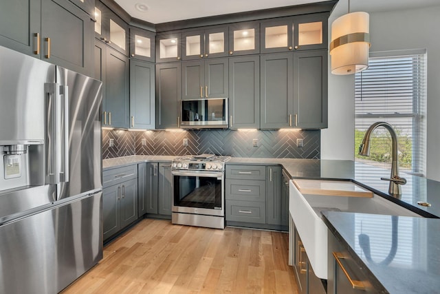 418 Mercomatic Dr, Nashville, TN 37209 - kitchen featuring stainless steel appliances, a sink, light wood finished floors, decorative light fixtures, and tasteful backsplash