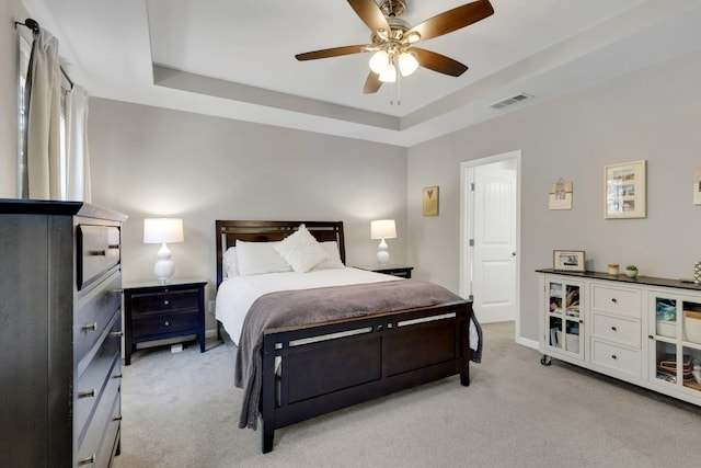 bedroom featuring light carpet, a ceiling fan, visible vents, and a raised ceiling
