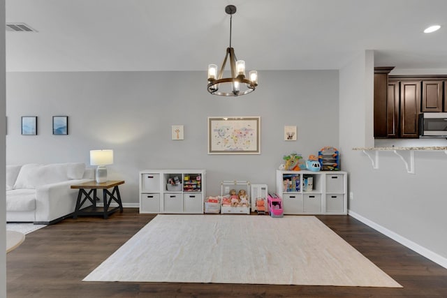 recreation room featuring dark wood-style flooring, visible vents, baseboards, recessed lighting, and a chandelier