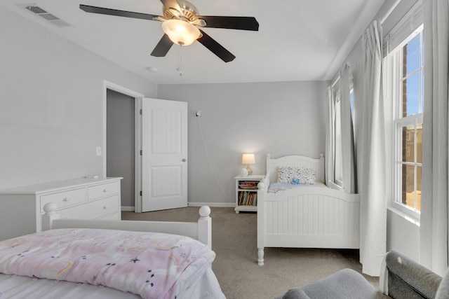 carpeted bedroom featuring baseboards, a ceiling fan, and visible vents