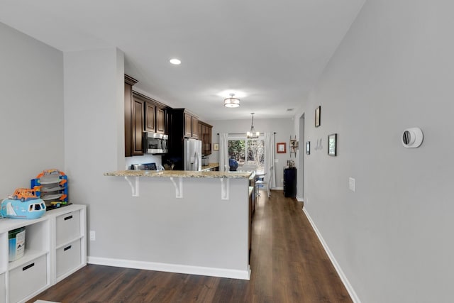 kitchen featuring dark wood-style floors, a kitchen bar, a notable chandelier, and appliances with stainless steel finishes
