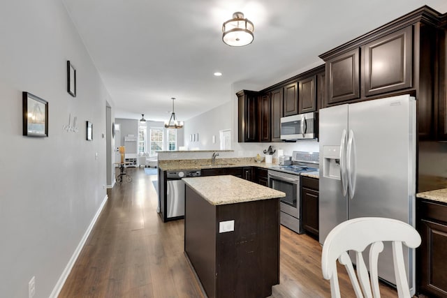 kitchen featuring stainless steel appliances, a center island, dark wood-style floors, a sink, and dark brown cabinetry
