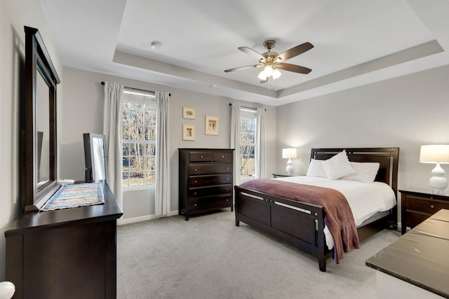 bedroom with baseboards, carpet flooring, multiple windows, and a raised ceiling