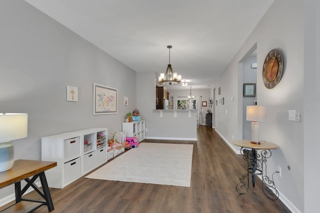 rec room featuring dark wood-type flooring, baseboards, and an inviting chandelier