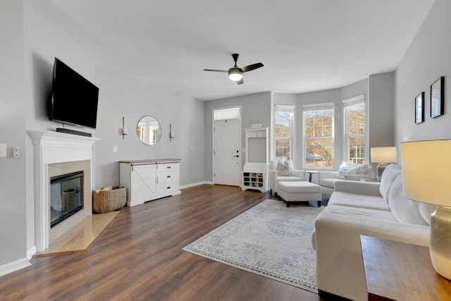 living room featuring baseboards, a fireplace, ceiling fan, and dark wood finished floors