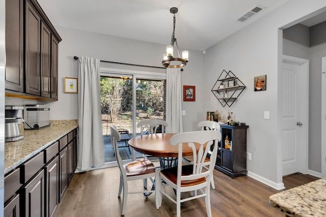 dining area with baseboards, a chandelier, wood finished floors, and visible vents