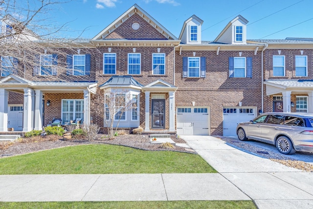 multi unit property featuring brick siding, a front lawn, driveway, and a garage