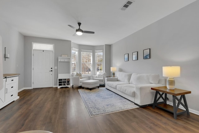 living room with baseboards, a ceiling fan, visible vents, and dark wood finished floors