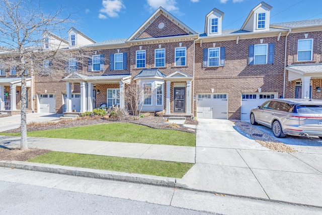 townhome / multi-family property featuring an attached garage, driveway, brick siding, and a front yard