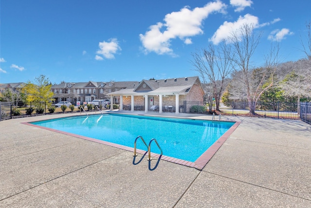 community pool with fence, a patio area, and a residential view