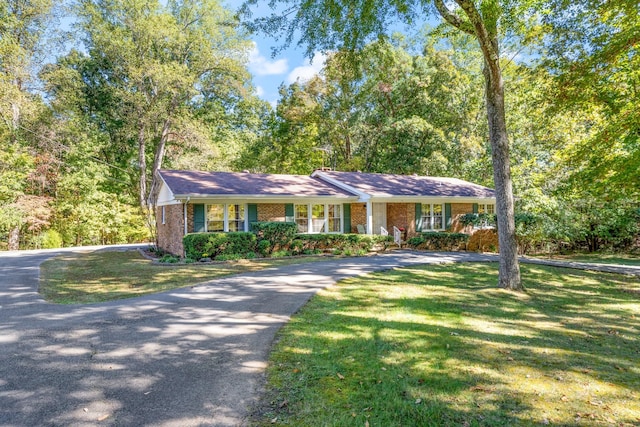 single story home featuring brick siding, a front yard, and aphalt driveway