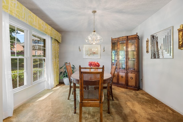 dining room with a chandelier, baseboards, a wealth of natural light, and light colored carpet