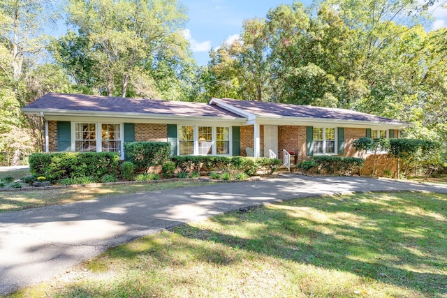 ranch-style home featuring brick siding, a front lawn, and aphalt driveway
