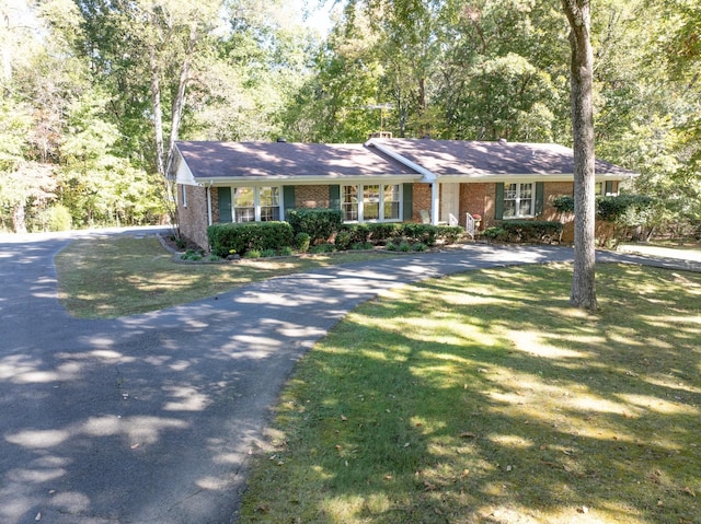 single story home featuring brick siding, a front lawn, and driveway