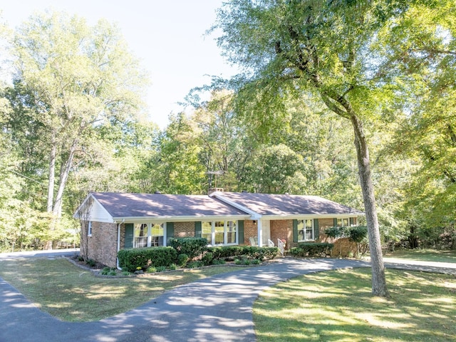 ranch-style house featuring a front lawn, brick siding, and aphalt driveway