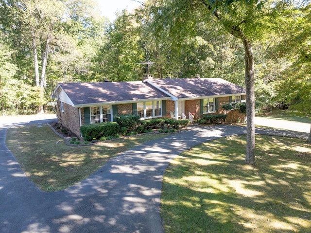 ranch-style home featuring brick siding, driveway, and a front yard