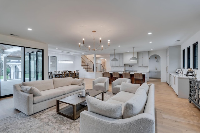 living area featuring recessed lighting, light wood-type flooring, stairway, and an inviting chandelier
