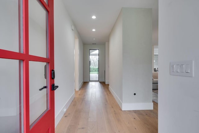 hallway with baseboards, light wood finished floors, and recessed lighting