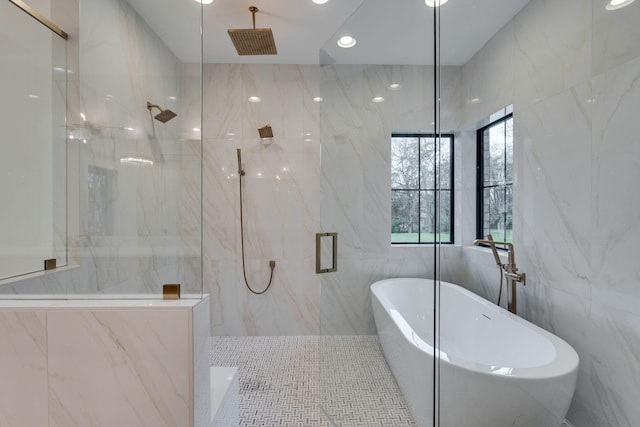 full bath featuring tile walls, a freestanding tub, and a marble finish shower