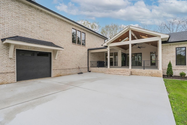 back of property with concrete driveway, brick siding, and ceiling fan