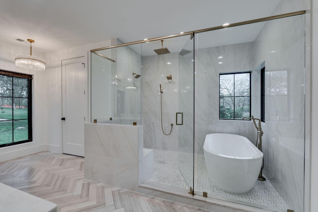 bathroom with a soaking tub, a marble finish shower, and an inviting chandelier