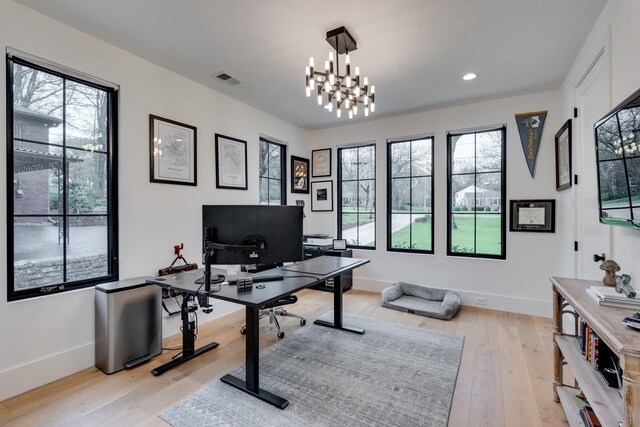 office space featuring light wood-style floors, a healthy amount of sunlight, baseboards, and visible vents