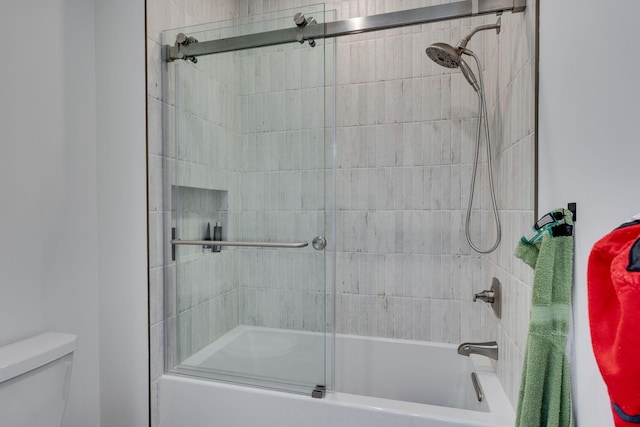 full bath featuring toilet and combined bath / shower with glass door