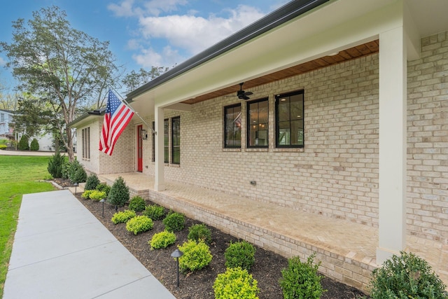view of home's exterior with brick siding, a ceiling fan, and covered porch