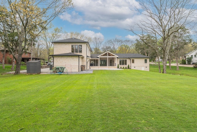 back of property with a lawn, brick siding, and a sunroom