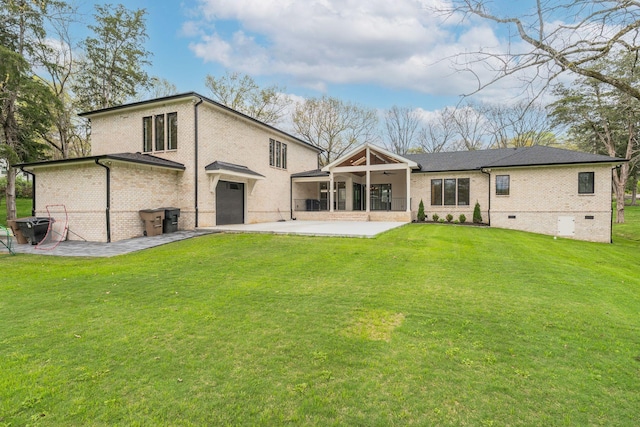 rear view of property featuring a yard, an attached garage, a patio area, crawl space, and brick siding