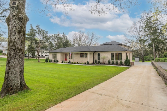 view of front facade featuring concrete driveway, a front lawn, and brick siding