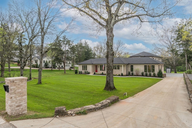 view of front of home featuring brick siding, driveway, and a front yard