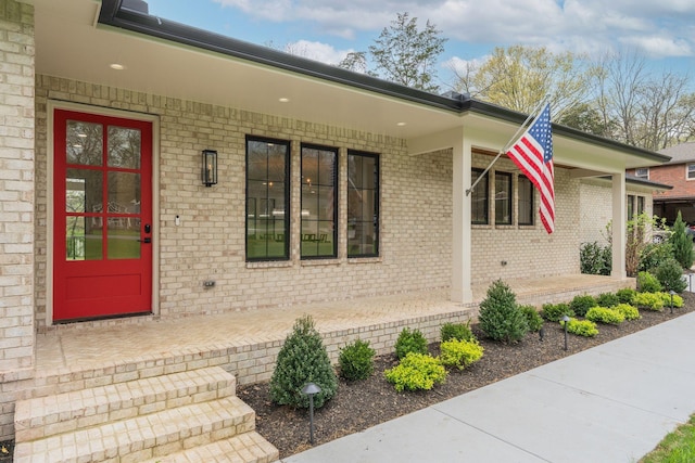 property entrance featuring a porch and brick siding