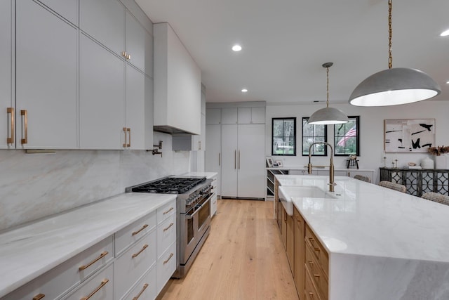 kitchen featuring custom exhaust hood, a large island with sink, light wood finished floors, double oven range, and recessed lighting